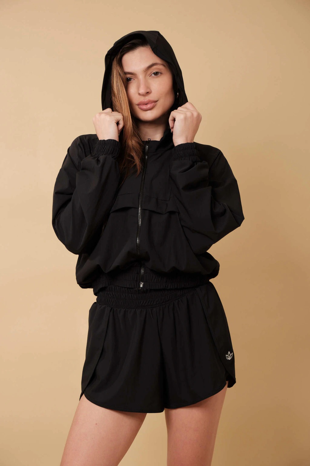 Modelo usando conjunto preto de jaqueta com capuz e short da Equifit