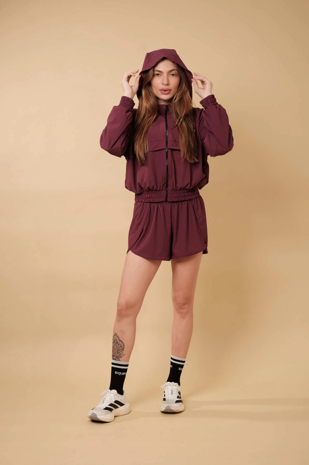 Modelo usando conjunto vinho de jaqueta com capuz e short da Equifit